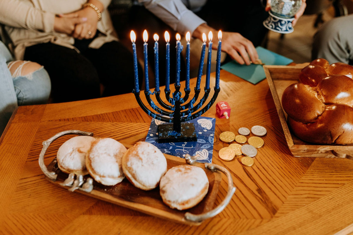 חנוכייה דולקת, סופגניות, חלה ומטבעות חנוכה על שולחן משפחתי